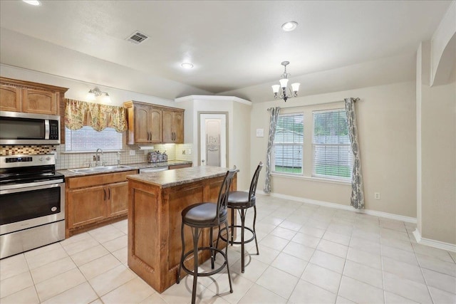 7385 Hidden Valley Dr, Beaumont, TX 77706 - kitchen featuring appliances with stainless steel finishes, a sink, tasteful backsplash, a center island, and a breakfast bar area