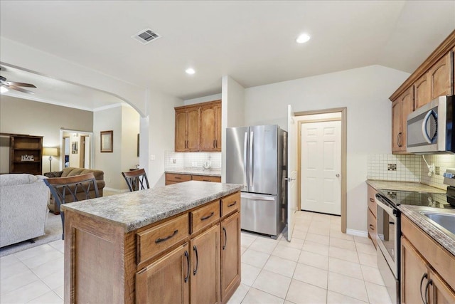 7385 Hidden Valley Dr, Beaumont, TX 77706 - kitchen with stainless steel appliances, arched walkways, backsplash, open floor plan, and light tile patterned flooring