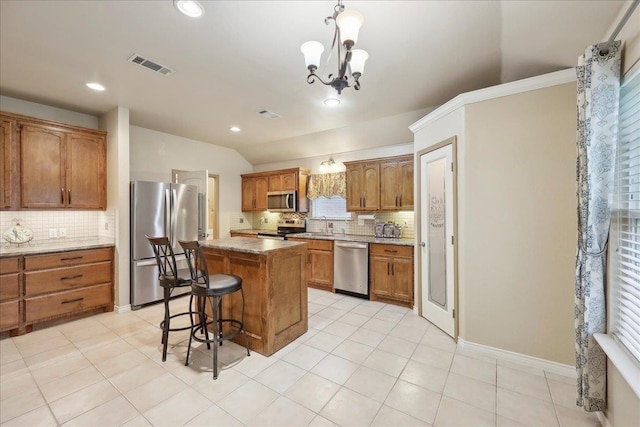 7385 Hidden Valley Dr, Beaumont, TX 77706 - kitchen with appliances with stainless steel finishes, tasteful backsplash, brown cabinets, a breakfast bar, and a center island