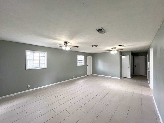 spare room featuring a ceiling fan, visible vents, a wealth of natural light, and baseboards