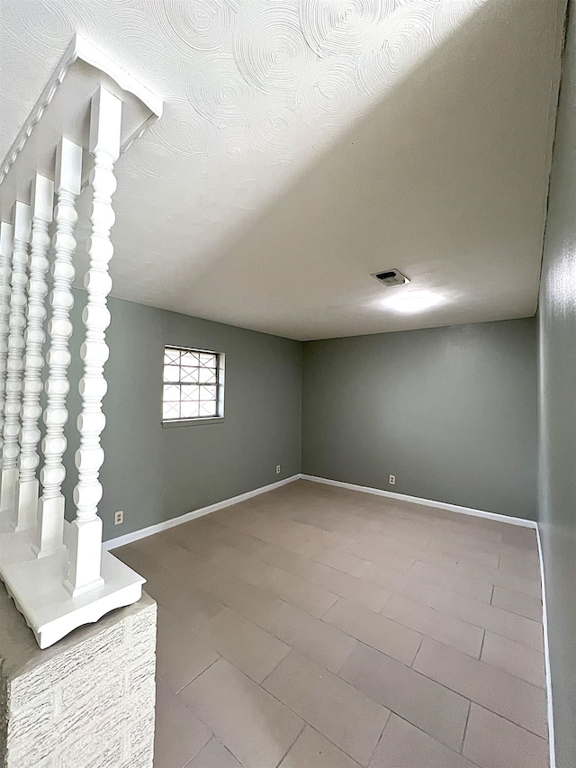 spare room featuring visible vents, a textured ceiling, and baseboards