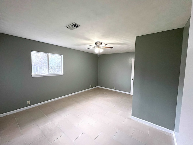 spare room featuring baseboards, visible vents, and ceiling fan