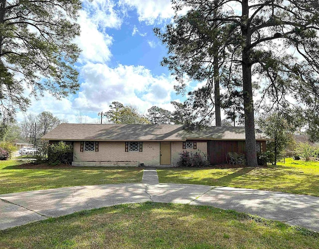 ranch-style home featuring driveway, brick siding, and a front yard