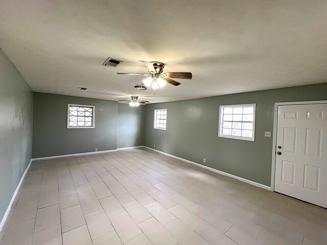 spare room featuring visible vents, ceiling fan, and baseboards