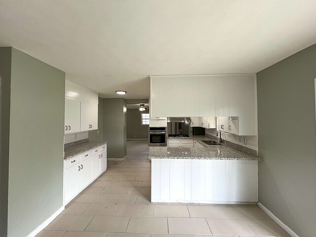 kitchen with oven, a ceiling fan, a sink, a peninsula, and white cabinets