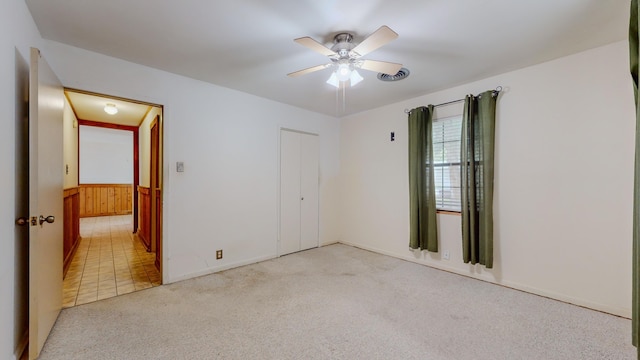 unfurnished room featuring ceiling fan, wood walls, and light carpet