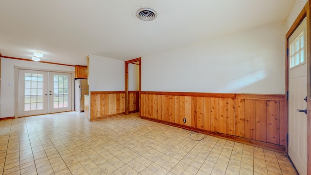 unfurnished room with french doors and wood walls