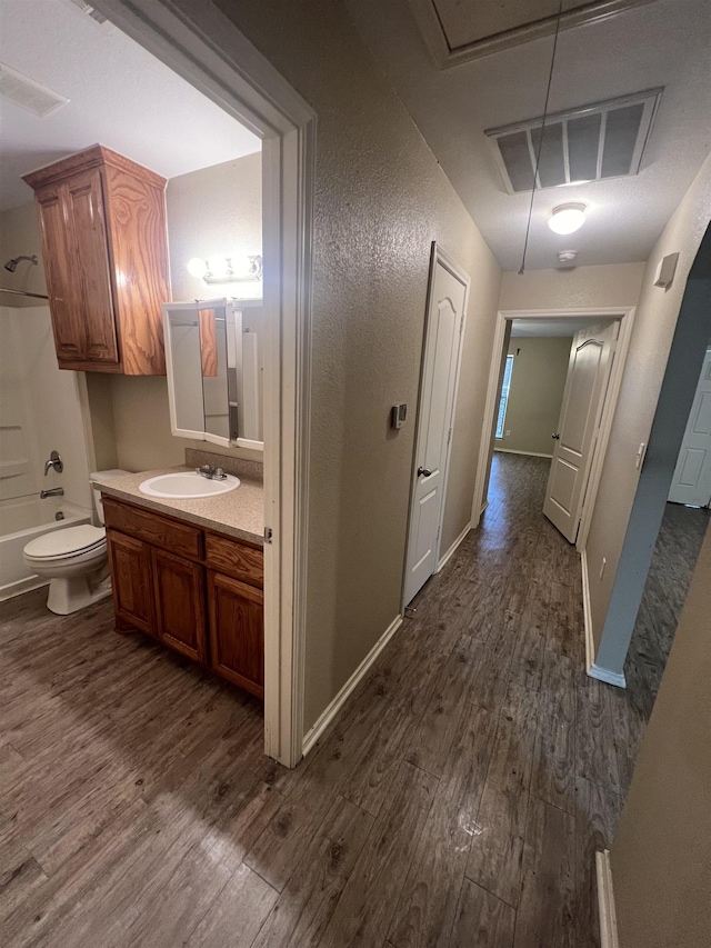 full bathroom with hardwood / wood-style flooring, vanity, shower / bath combination, and toilet