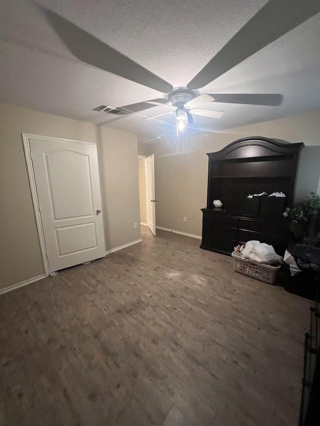 unfurnished bedroom featuring dark wood-type flooring, ceiling fan, and a textured ceiling