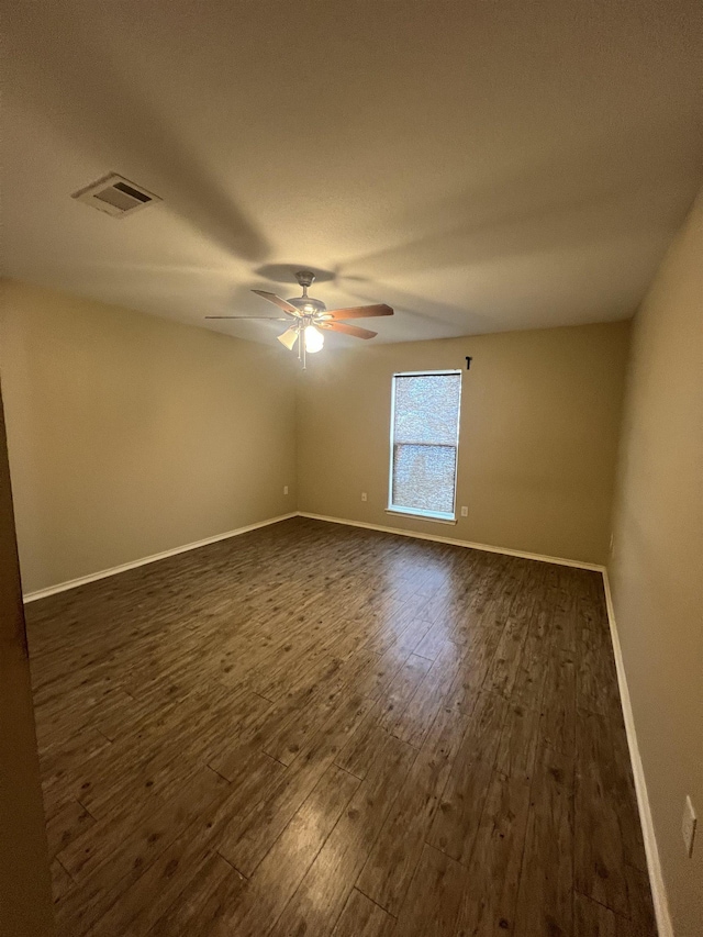 empty room featuring dark wood-type flooring and ceiling fan