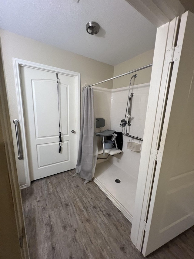 bathroom featuring wood-type flooring, a shower with shower curtain, and a textured ceiling