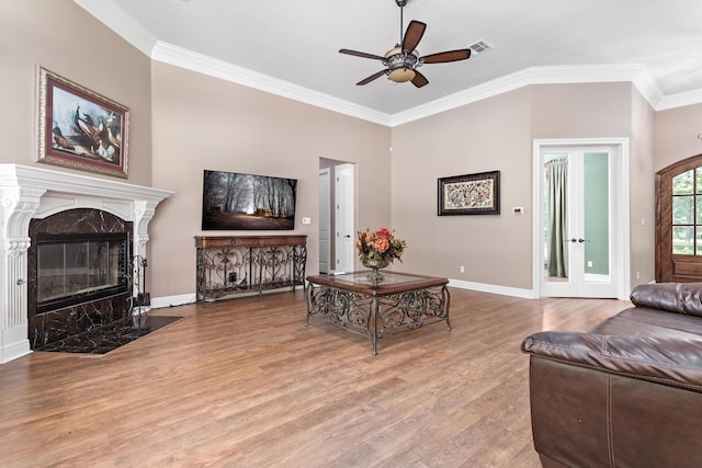 living room with ceiling fan, crown molding, a fireplace, and light hardwood / wood-style floors