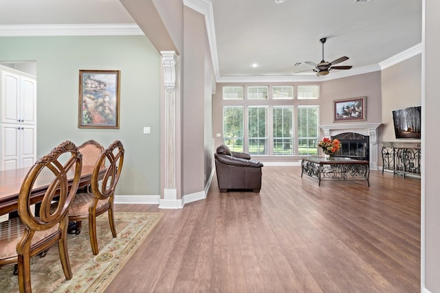 dining area with hardwood / wood-style flooring, ceiling fan, crown molding, and a premium fireplace