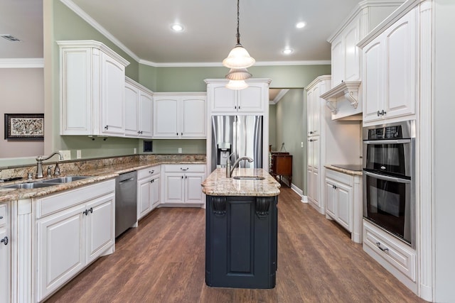 kitchen featuring decorative light fixtures, sink, a kitchen island with sink, stainless steel appliances, and white cabinets