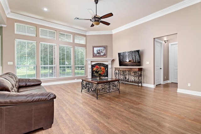 living room with ceiling fan, wood-type flooring, a fireplace, and crown molding