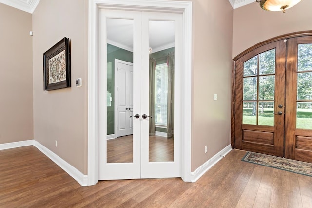 foyer entrance with hardwood / wood-style floors, ornamental molding, and french doors