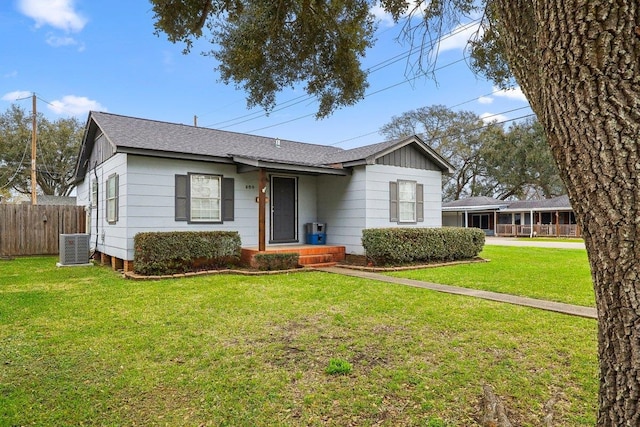 view of front of home with a front yard, cooling unit, fence, and roof with shingles