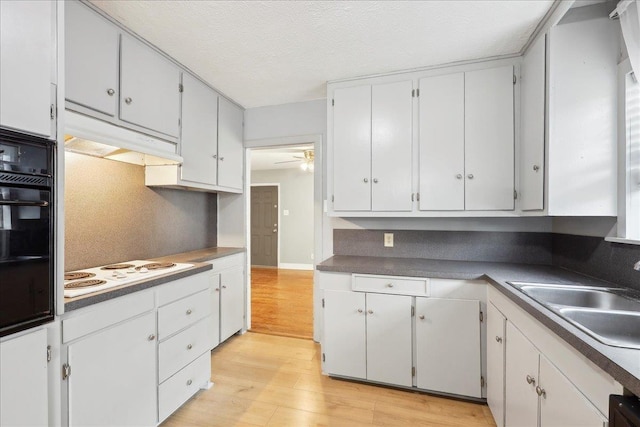 kitchen featuring light hardwood / wood-style flooring, black oven, sink, white cabinets, and white electric stovetop