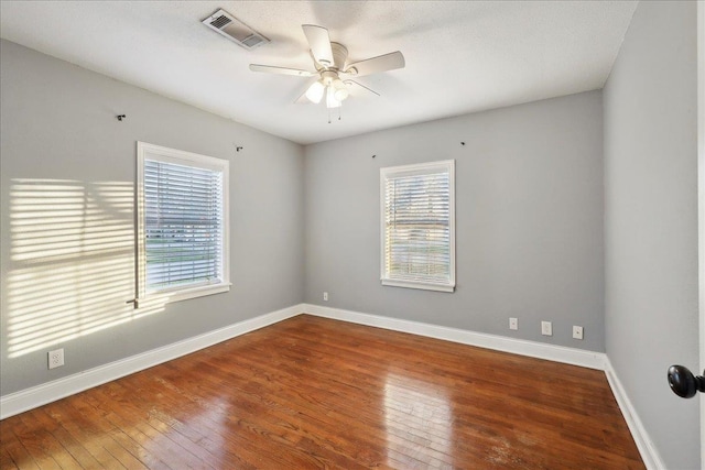 spare room with ceiling fan, wood-type flooring, and a healthy amount of sunlight