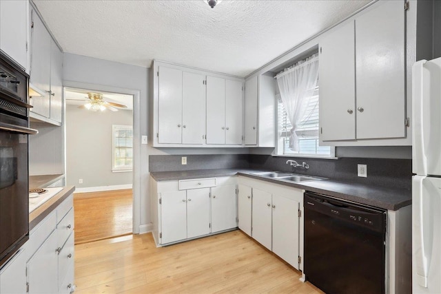 kitchen with sink, white cabinetry, black appliances, and light hardwood / wood-style floors