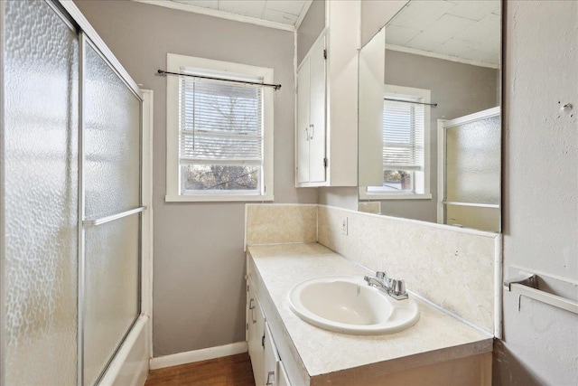 bathroom with hardwood / wood-style flooring, vanity, combined bath / shower with glass door, and a healthy amount of sunlight