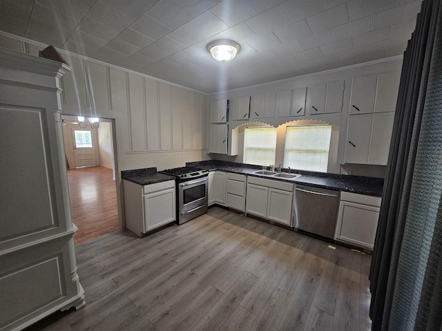 kitchen featuring sink, light wood-type flooring, ornamental molding, a healthy amount of sunlight, and stainless steel appliances