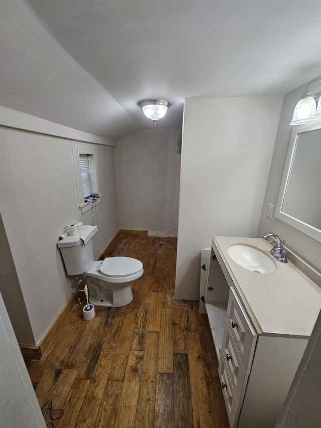 bathroom with vanity, wood-type flooring, lofted ceiling, and toilet