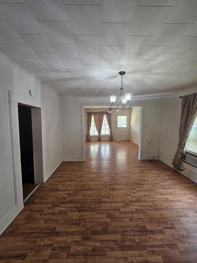 spare room with dark wood-type flooring and an inviting chandelier