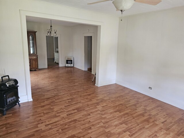 spare room featuring heating unit, wood-type flooring, and ceiling fan with notable chandelier