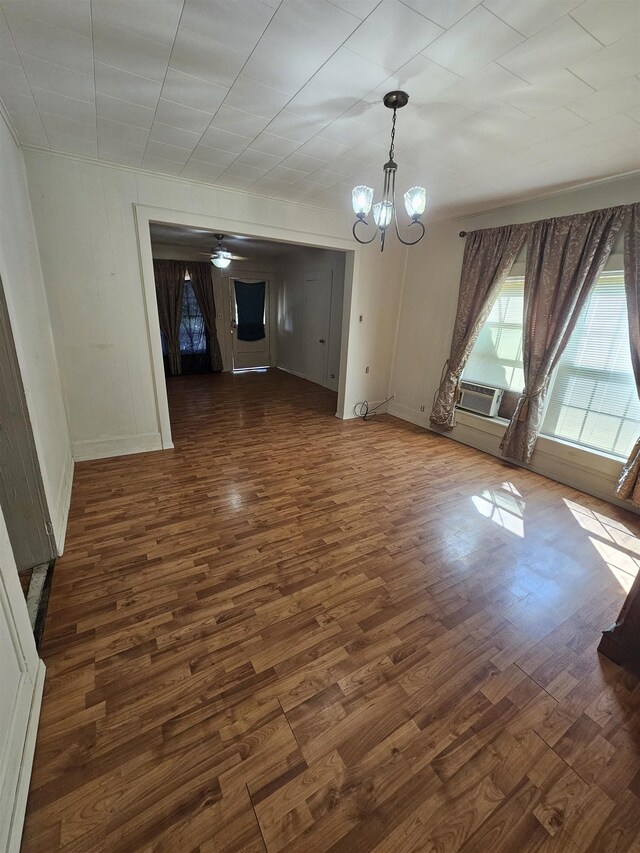 unfurnished dining area with an AC wall unit, dark hardwood / wood-style flooring, and ceiling fan with notable chandelier