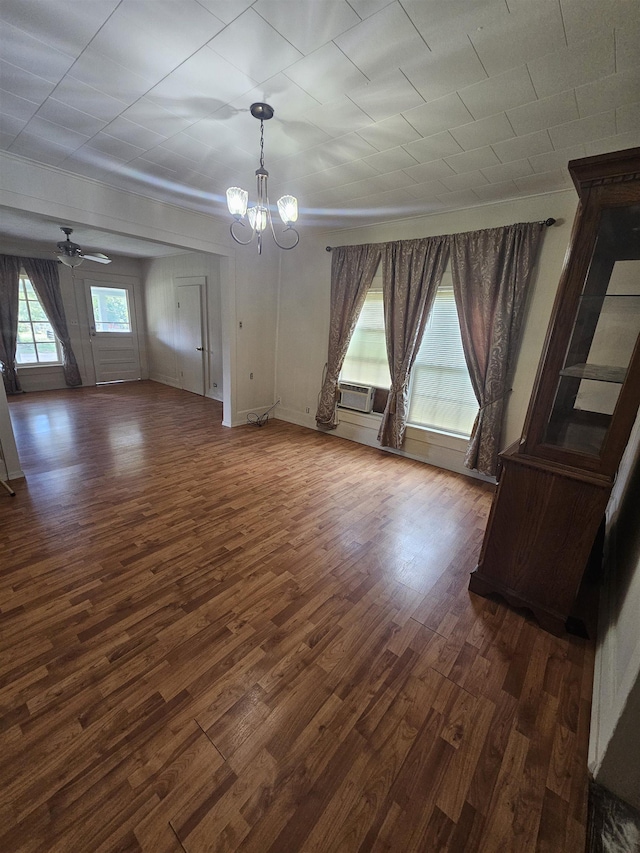 unfurnished dining area with ceiling fan with notable chandelier and dark hardwood / wood-style floors