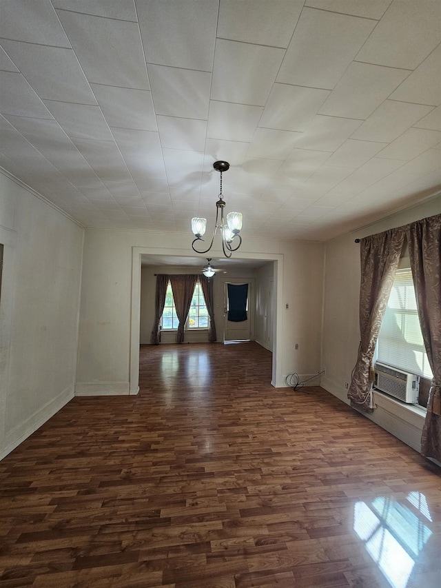 unfurnished living room featuring cooling unit, dark wood-type flooring, and an inviting chandelier