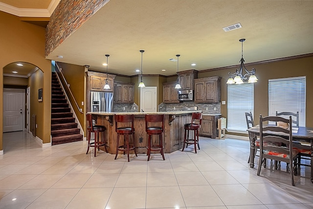 3812 Debbie Ave, Groves, TX 77619 - kitchen with appliances with stainless steel finishes, light tile patterned floors, decorative backsplash, arched walkways, and crown molding