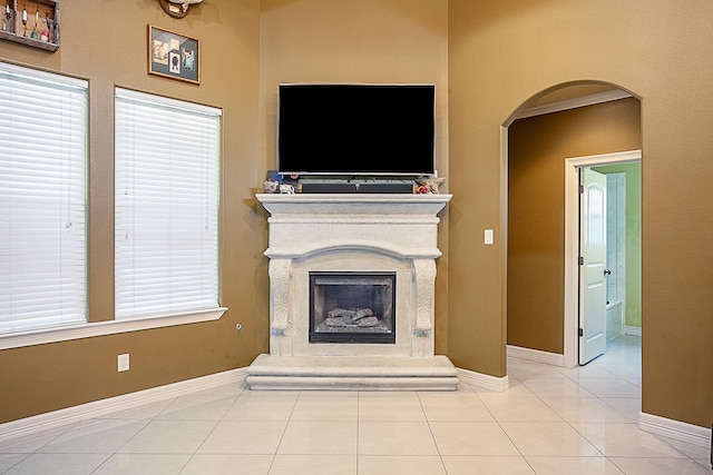 3812 Debbie Ave, Groves, TX 77619 - unfurnished living room featuring tile patterned flooring, arched walkways, a fireplace with raised hearth, and baseboards