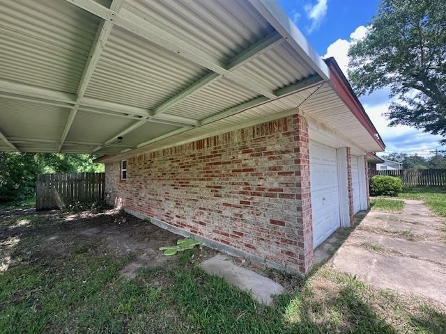 320 Meadow Dr, Bridge City, TX 77611 - view of home's exterior with fence, brick siding, and a garage