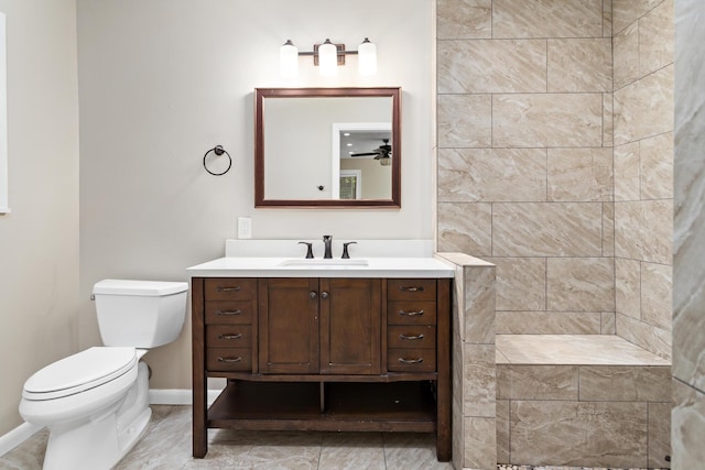 full bath with toilet, vanity, baseboards, and tiled shower