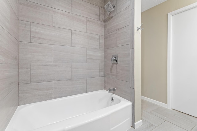 full bath featuring baseboards and washtub / shower combination