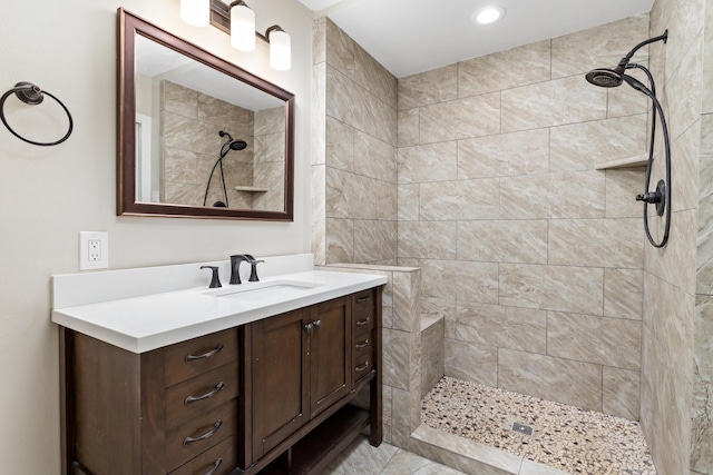 full bathroom featuring a tile shower and vanity