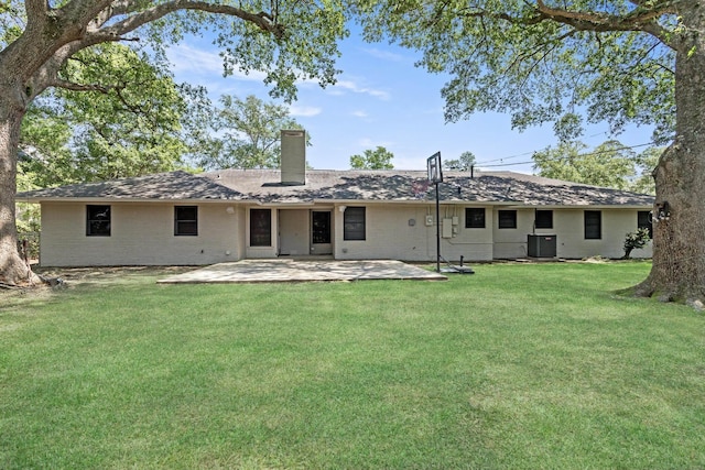 rear view of house with central AC, brick siding, a patio area, a chimney, and a yard