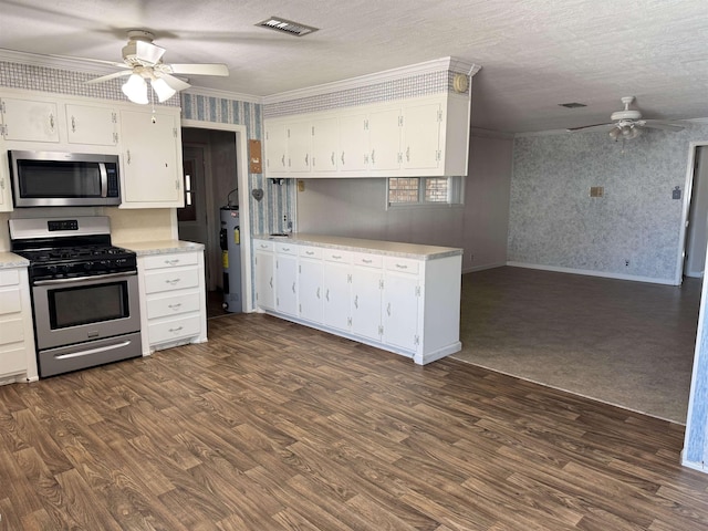 kitchen with visible vents, wallpapered walls, water heater, dark wood-type flooring, and appliances with stainless steel finishes