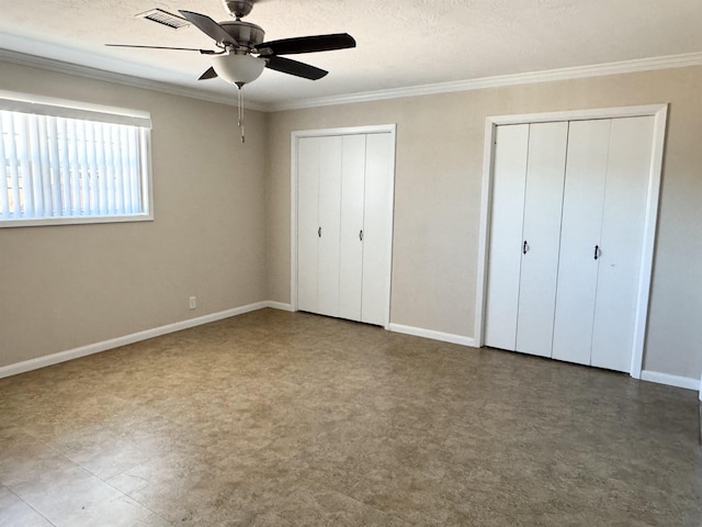 unfurnished bedroom with visible vents, two closets, crown molding, and baseboards