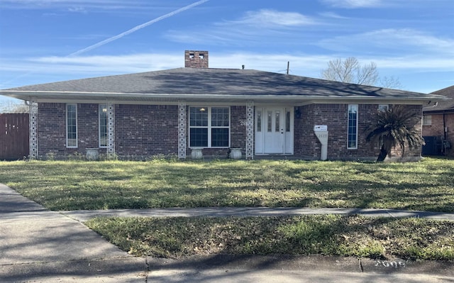 ranch-style house featuring brick siding, a chimney, a front lawn, and roof with shingles