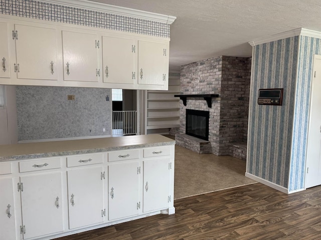 kitchen featuring dark wood finished floors, light countertops, a fireplace, white cabinets, and a textured ceiling