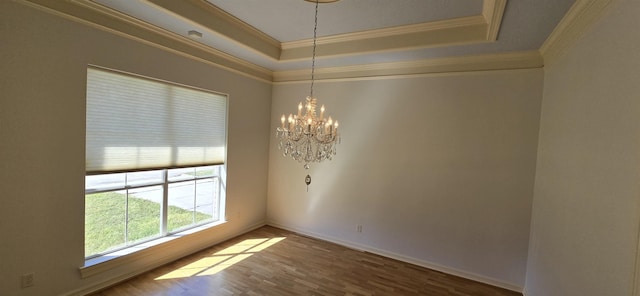 unfurnished room with crown molding, a tray ceiling, and wood finished floors