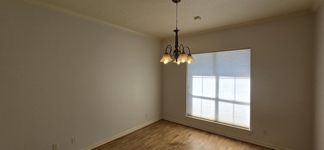 unfurnished room featuring a notable chandelier, ornamental molding, baseboards, and wood finished floors