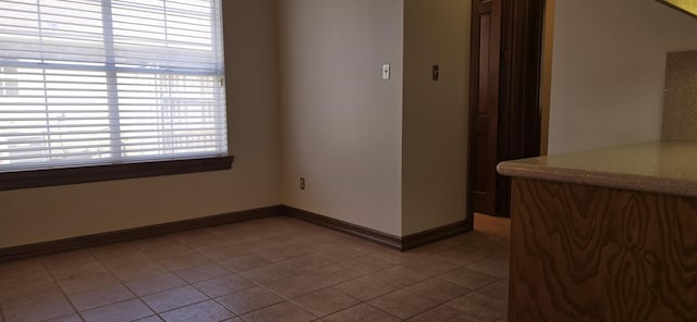 spare room featuring baseboards and tile patterned flooring