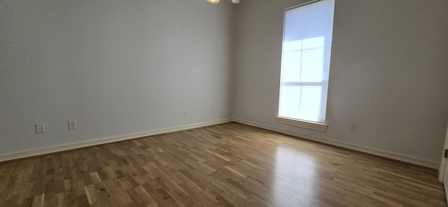 empty room featuring a wealth of natural light, baseboards, and wood finished floors