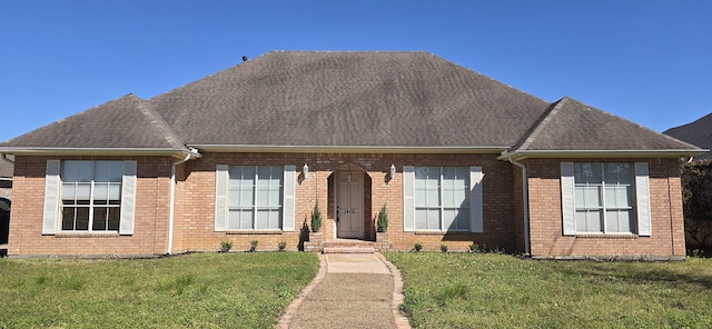 view of front of home featuring brick siding, a shingled roof, and a front yard