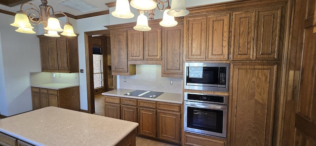 kitchen featuring built in microwave, oven, light countertops, black electric stovetop, and a chandelier