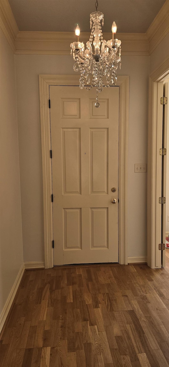 doorway featuring a notable chandelier, baseboards, dark wood-style flooring, and ornamental molding